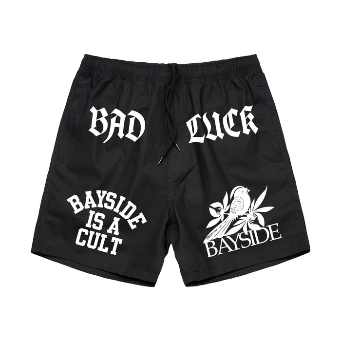 Black Bayside AS Colour Beach Shorts featuring white heat transfer text reading BAD LUCK, BAYSIDE IS A CULT, and BAYSIDE, along with a graphic of a bird on a branch—perfect casual shorts for an effortless look.