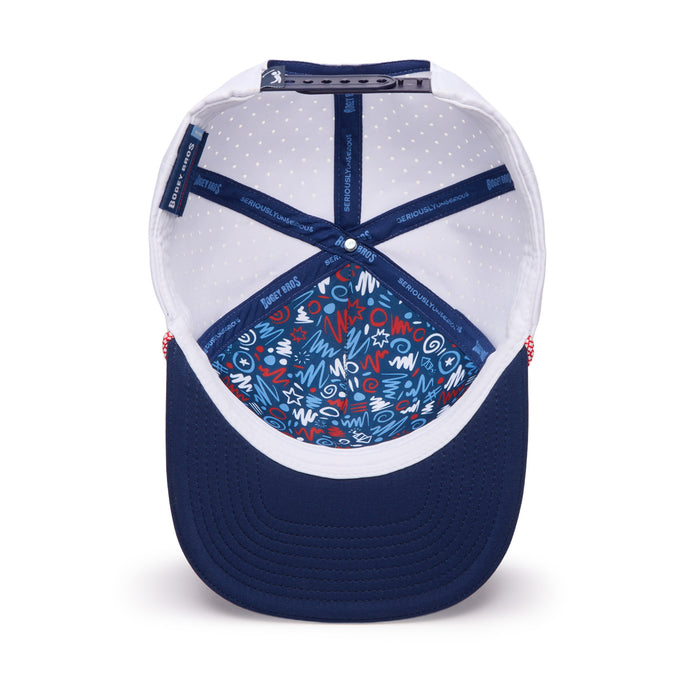 Blue and white baseball cap viewed from above, showing the inside. The inner crown lining features a colorful abstract pattern with red, white, and blue shapes. The sweatband and brim are navy blue, and the inner panel has white fabric with small polka dots.