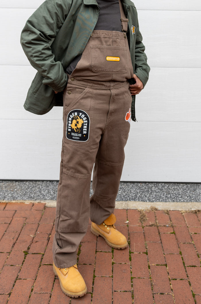 Close up of brown We Us overalls.