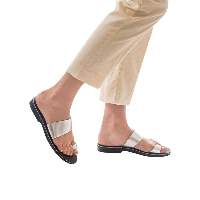 Model wearing Abra silver, handmade leather slide sandals with toe loop
