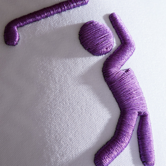 Closeup of purple embroidered figure on sweat stain resistant white fabric, stitched with thick thread for a 3D effect, featured on the Bogeyman - White/Purple Performance Golf Hat - Snapback.