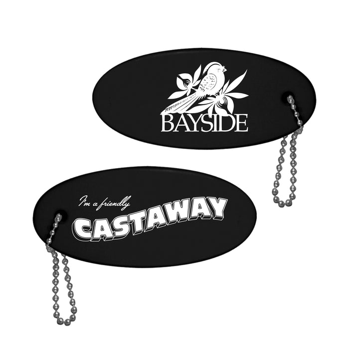 Two black oval keychains with bead chains: one features “BAYSIDE” with a bird and leaves, the other says “I’m a friendly CASTAWAY” in bold white letters. Brand: Bayside.