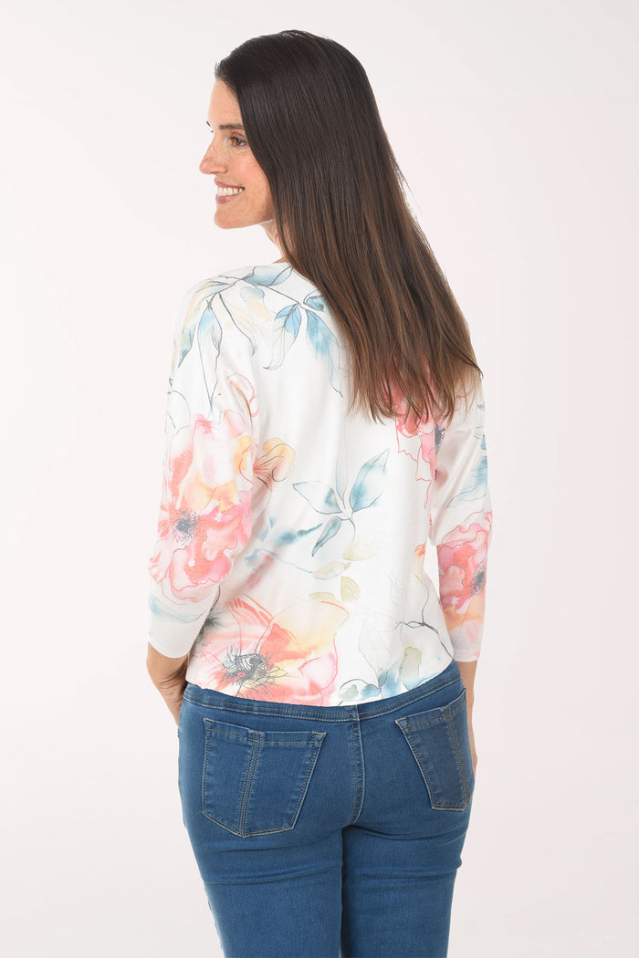 Woman wearing a floral long-sleeve top and blue jeans on a white background