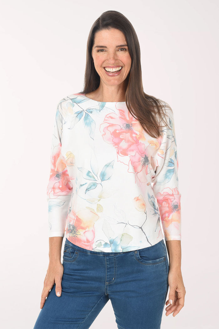 Woman wearing a floral long-sleeve top and blue jeans on a white background