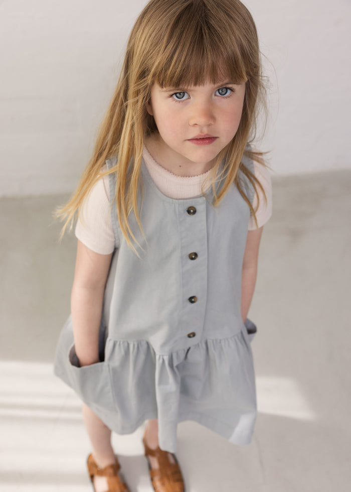 Wearing a buttonless blue chino dress with buttons and a bright red t-shirt.