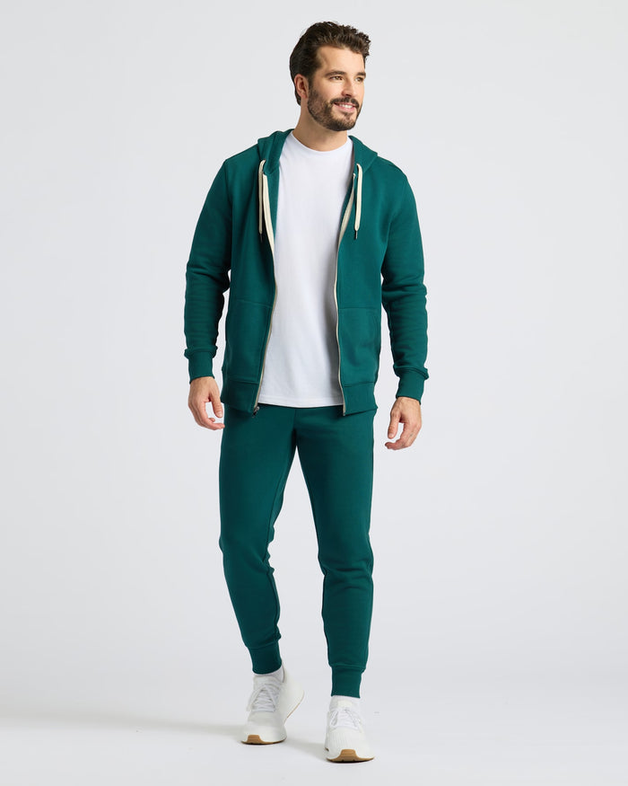 Model wearing Deep Emerald Fleece French Terry Joggers with hoodie and sneakers.