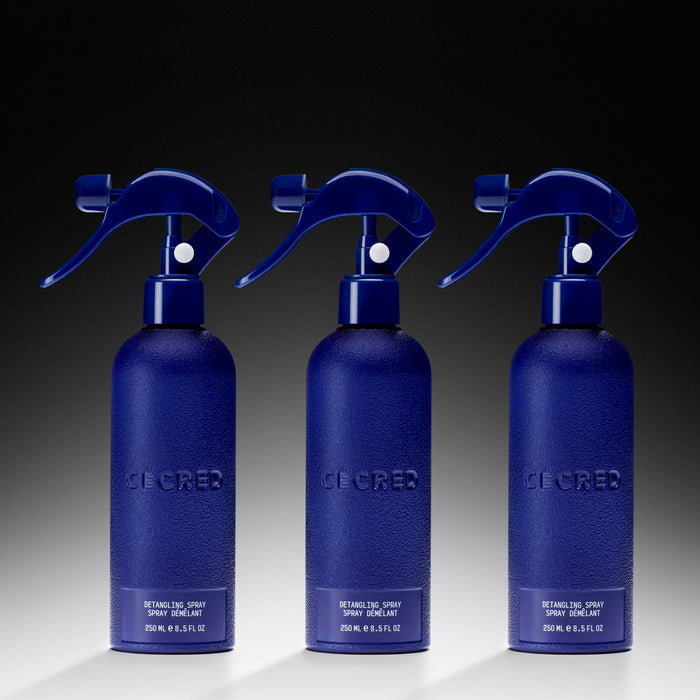 Three Cécred Detangling Spray bottles lined up on a dark gradient background