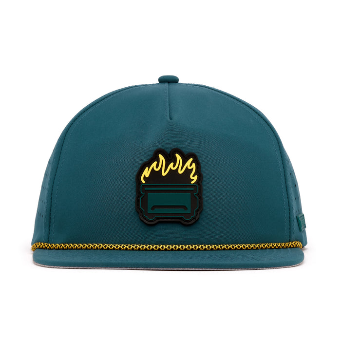 The Dumpster Fire Unstructured Flat Bill Snapback Hat features a teal design, gold rope on the brim, and a front patch with a black dumpster and yellow flames. Made from performance material with a structured crown and no visible branding.