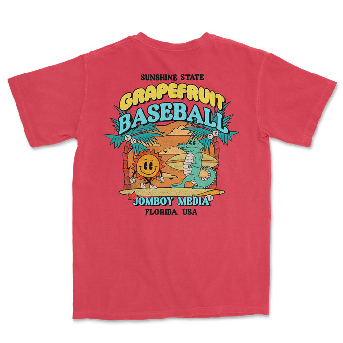Pink Comfort Colors T-shirt featuring a colorful grapefruit baseball graphic with a sun, palm trees, and playful characters.