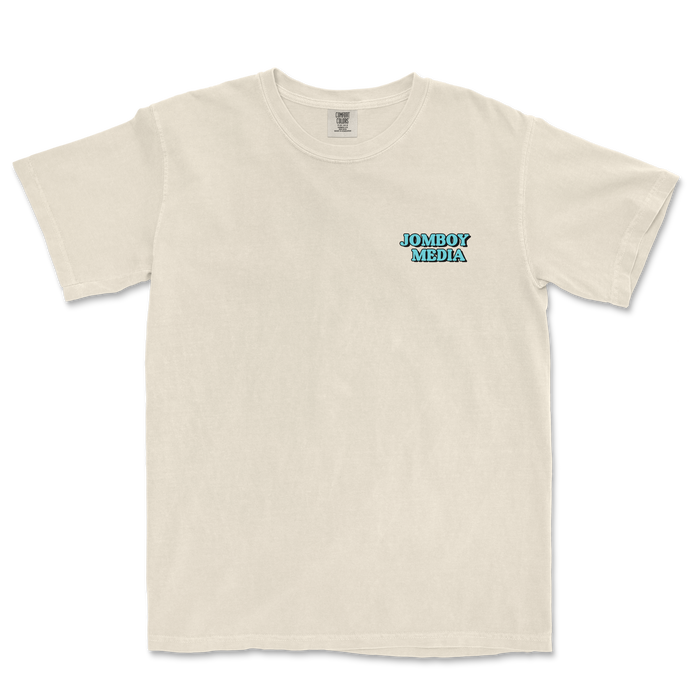 Beige Comfort Colors T-shirt with "JOMBOY MEDIA" in blue and black text on the left chest area.