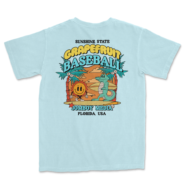 Light blue Comfort Colors T-shirt featuring a colorful grapefruit-themed baseball design with palm trees, a smiling sun, and a crocodile.