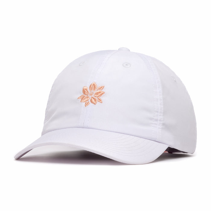 The In Bloom - Dad Hat is a white, unstructured cap with a curved brim and peach embroidered flower at the front. Made from performance material, it features stitched eyelets for ventilation and offers a relaxed fit.