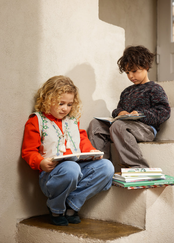 Kids' sweater in cream color with green embroidery, worn by two children.