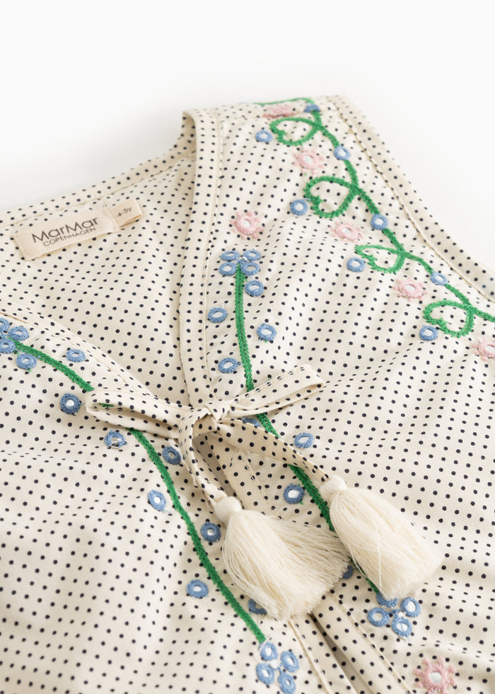 Checkedered children's vest with green embroidery, front opening and white fringe at the bottom