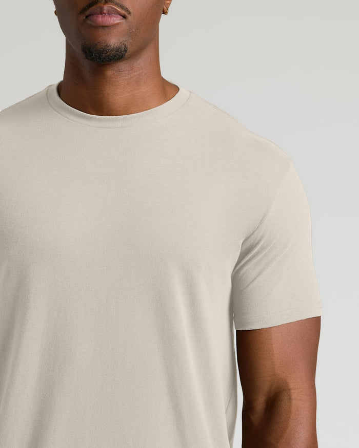Man wearing a plain beige t-shirt against a light gray background