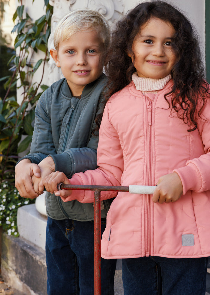 Girl in pink thermal jacket standing with scooter next to a boy