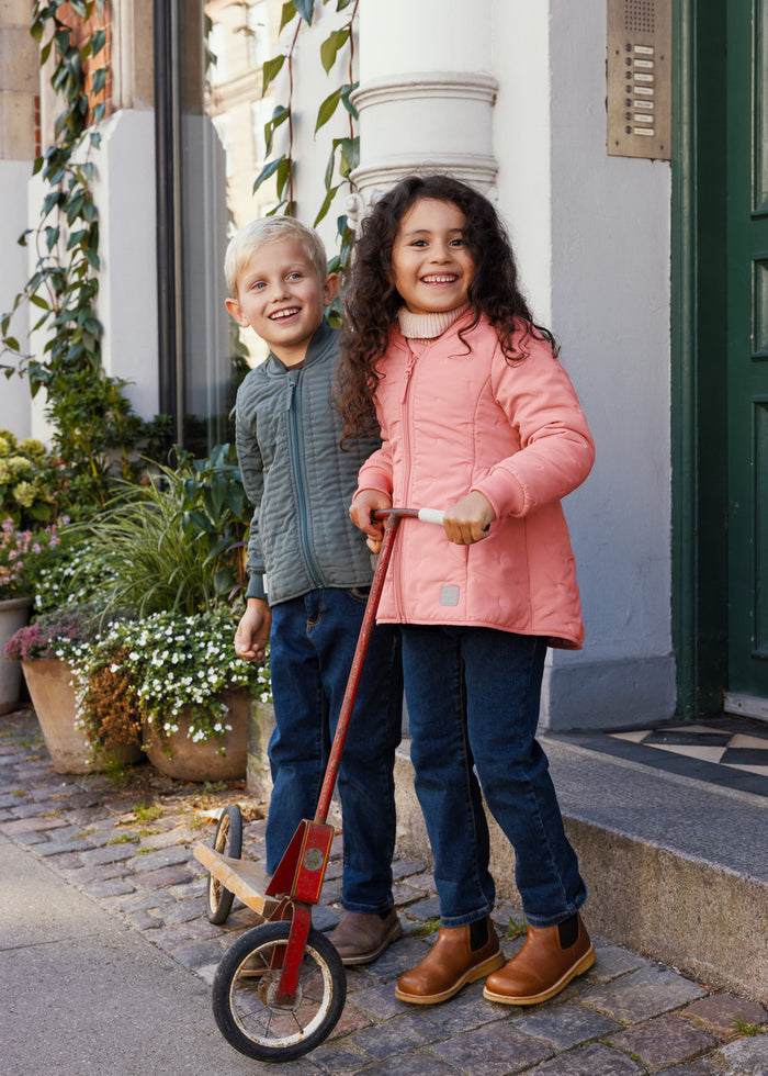 Girl in pink thermal jacket standing with scooter next to a boy