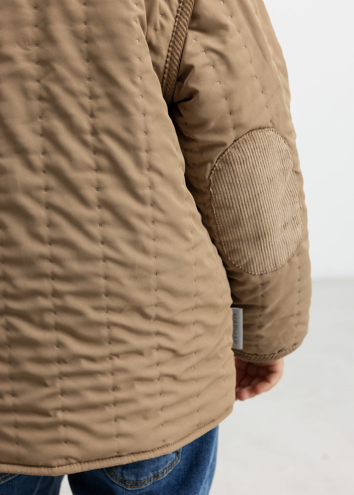 Close-up of pocket and quilted structure on brown thermal jacket