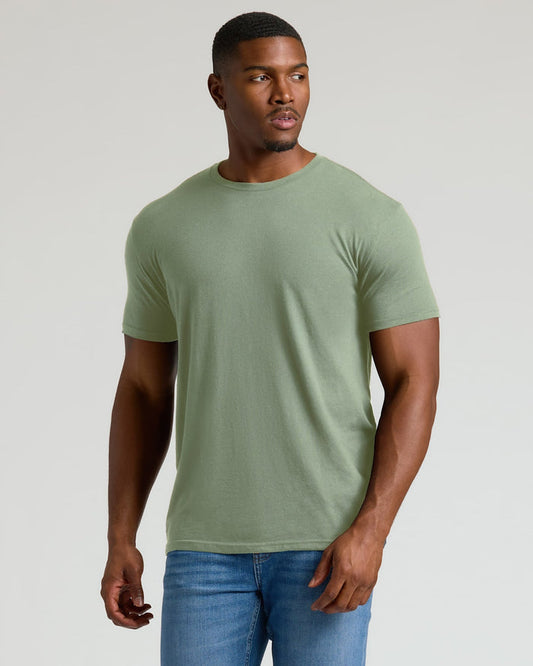 Man wearing a green t-shirt and blue jeans against a plain background