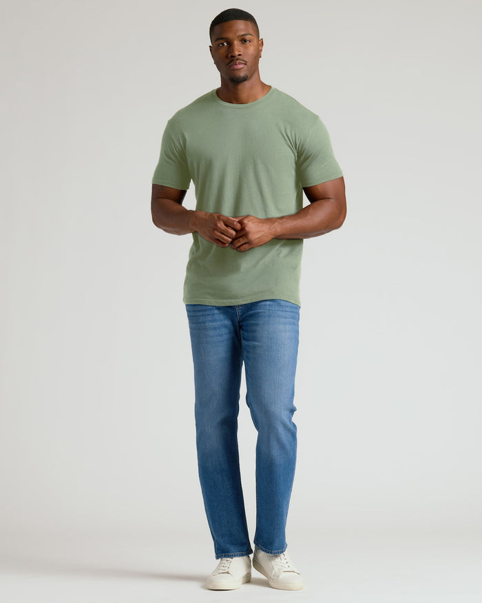 Man wearing a green t-shirt and blue jeans on a white background