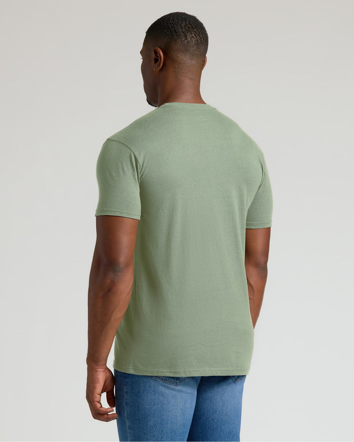 Man wearing a green t-shirt and blue jeans on a light gray background
