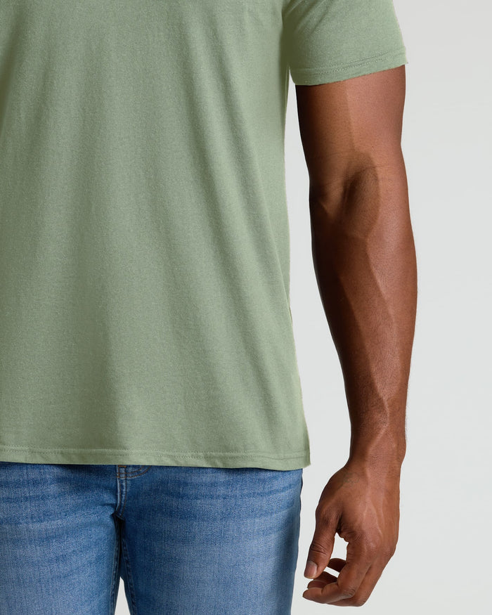 Person wearing a green t-shirt and blue jeans on a plain background