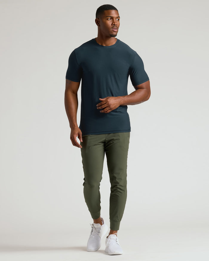 Man wearing a dark green t-shirt and olive green pants on a white background