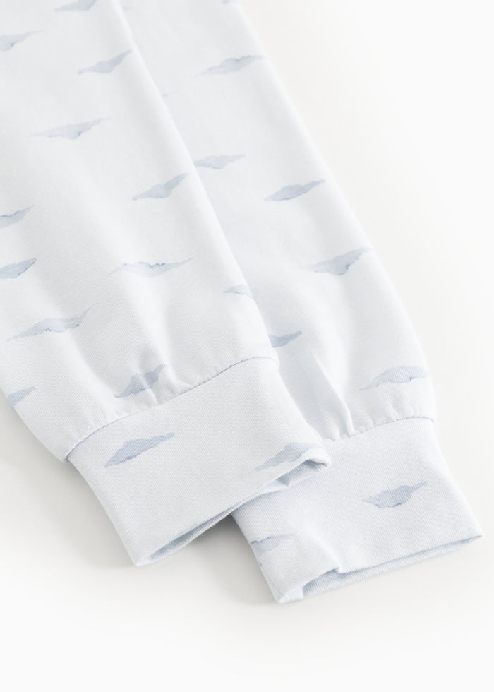 Kids sleepwear close-up: blue whales on white fabric and elastic edge at the leg hem.