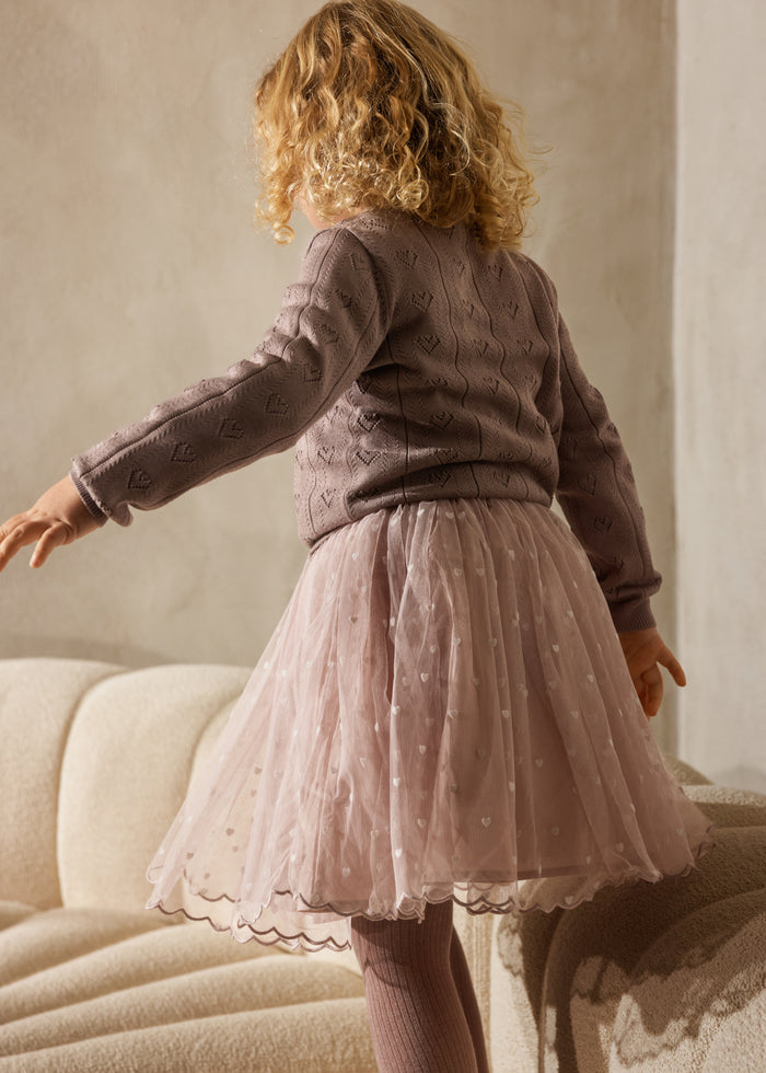 Pink skirt with small white hearts, a fitted waist, and a fringe hem.