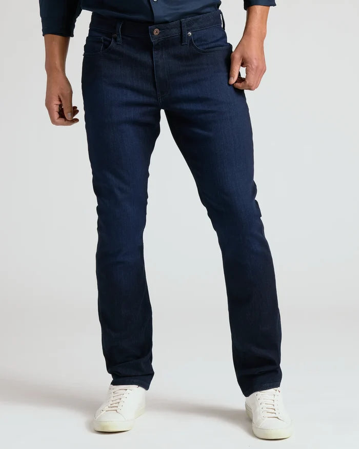 Person wearing dark blue jeans and white sneakers on a light gray background