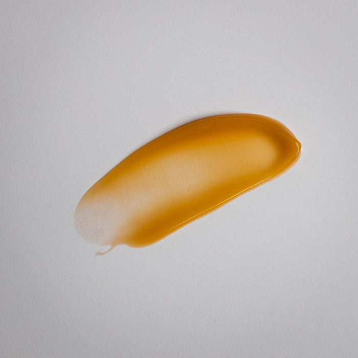 Close-up of a smooth amber gel swatch on a light surface representing the texture of Tightening Eye Gel | Alchimie Forever skincare product.