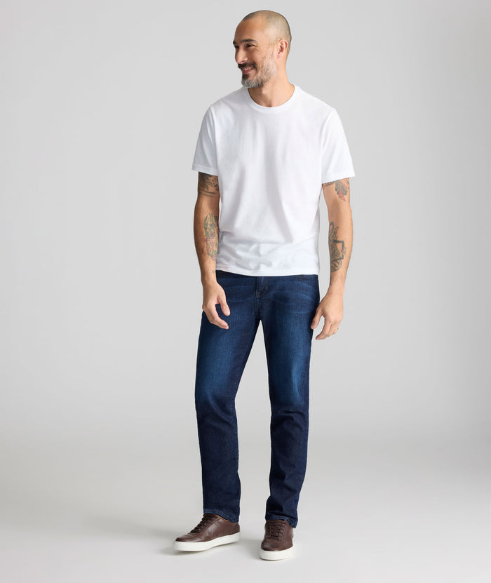 Man wearing a white t-shirt and blue jeans on a plain background