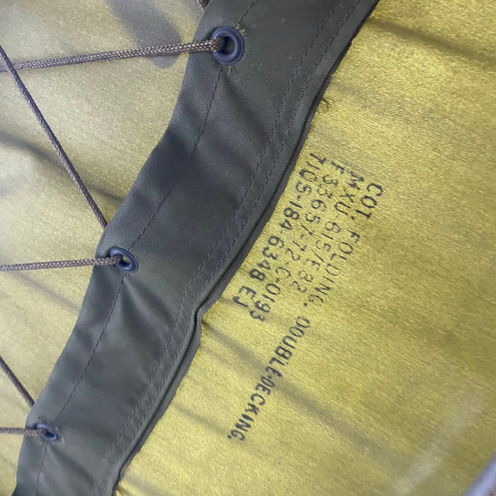 Close-up of a military-style cot with visible branding and text.