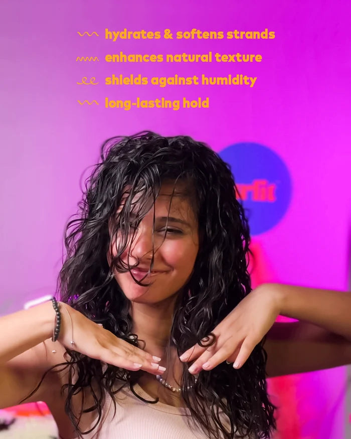 Young woman with natural wavy hair smiling with soft, defined, frizz-free waves after using Curlit products