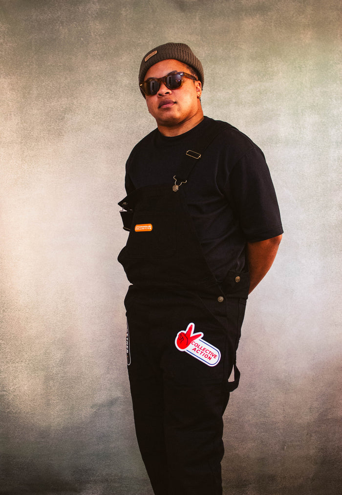 Model wearing We Us overalls, a We Us beanie, and sunglasses.