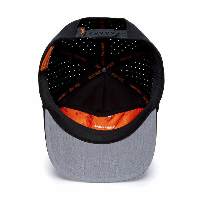 A look inside the Wingin' It - Unstructured Flat Bill Hat - Snapback shows a black cap with a gray flat brim, orange interior accents, HOOTERS logo on bands, perforated crown fabric, and an adjustable snapback closure.